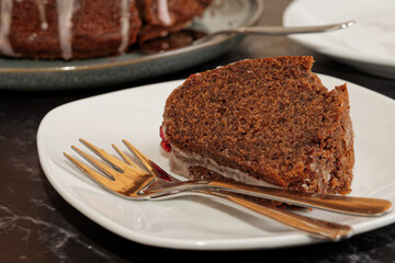 Close up of mulled wine sponge cake with icing and pomegranate seeds.
