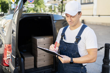 A male courier in the form of a driver delivering an order to a courier company at home.