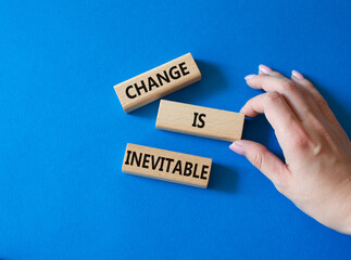 Change is Inevitable symbol. Wooden blocks with words Change is Inevitable. Beautiful blue background. Businessman hand. Business and Change is Inevitable concept. Copy space.