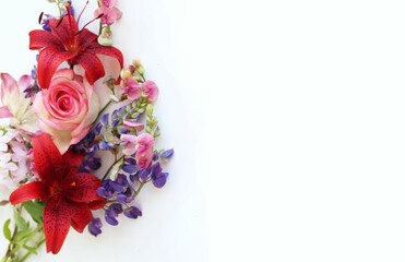 Red and pink lilies in a festive bouquet on a white background. A bright floral arrangement. Background for a greeting card.