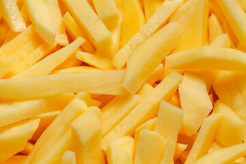 Potatoes, cut into strips, preparation for frying fries, close-up, selective focus