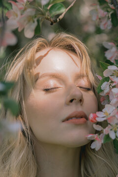 Portrait Of A Beautiful Woman Who Smells Flowers, Blooming Apple Orchard, Long Blond Hair, Spring Time