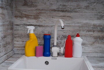 kitchen sink with bottles of cleaning products, Cleaning supplies and tools on the kitchen countertop