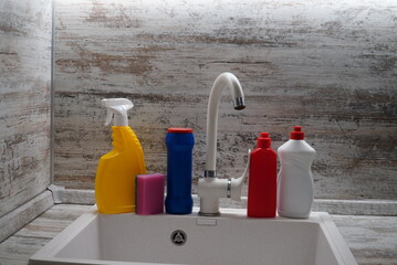 kitchen sink with bottles of cleaning products, Cleaning supplies and tools on the kitchen countertop