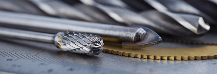 set of different drill bits,thread tap and mill cutters with caliper ruler on steel plate...