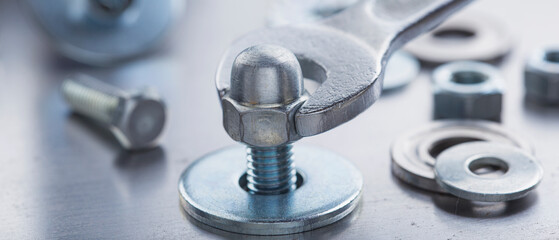 Wrench tightens steel cap nut in steel billet. Spanner, bolt, screw and nuts.
