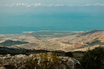 Beautiful landscape scene with brown rocky hills and blue sea reflected from the sky