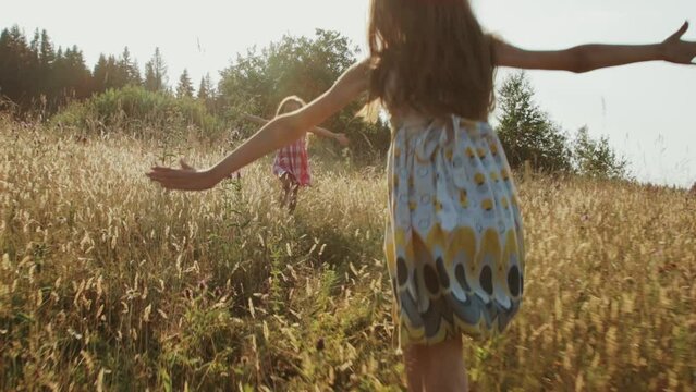 Two girls runing towards each other on a summer meadow