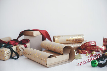 Wrapping stylish christmas gifts. Modern gift boxes, red and green ribbons, golden wrapping paper, ornaments and scissors on white background. Merry Christmas! Atmospheric winter time