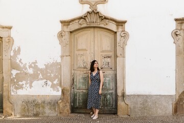 Fototapeta na wymiar Beautiful shot of an attractive female against an old typical door in Portugal