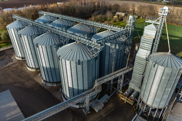 Obraz premium aerial view on rows of agro silos granary elevator with seeds cleaning line on agro-processing manufacturing plant for processing drying cleaning and storage of agricultural products