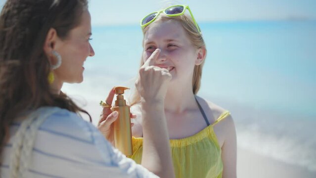 happy stylish mother and teenage daughter with sunscreen at the beach.
