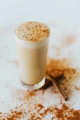 Closeup shot of a glass of a cinnamon mocha shake, surrounded with cinnamon sticks and powder