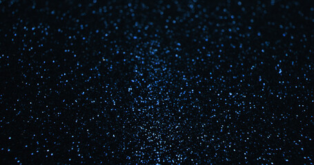 Bokeh sparkles. Shimmering background. Glamour radiance. Defocused blue color shiny light particles texture on dark black abstract copy space wallpaper.