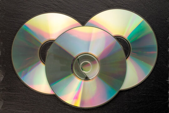 Three CD-R discs on slate stone, macro, top view.