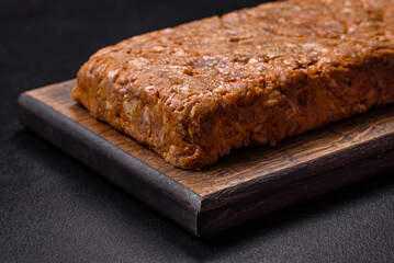 Tasty meat brawn or roll on a wooden cutting board with spices and herbs