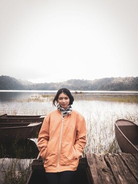 Vertical shot of an Indonesian female by the Tamblingan lake on a foggy day