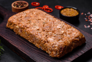 Tasty meat brawn or roll on a wooden cutting board with spices and herbs