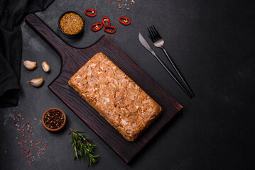 Tasty meat brawn or roll on a wooden cutting board with spices and herbs