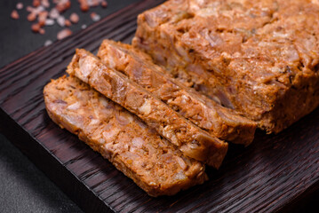 Tasty meat brawn or roll on a wooden cutting board with spices and herbs