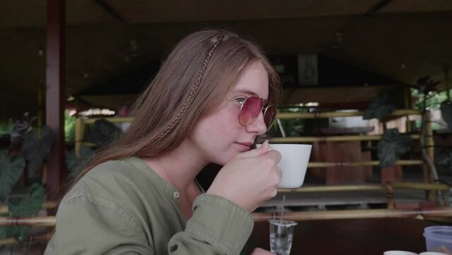 Closeup of a female tourist trying the civet coffee at a restaurant in Bali, Indonesia