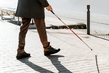 Blind man close-up with a walking stick. Walking down the street