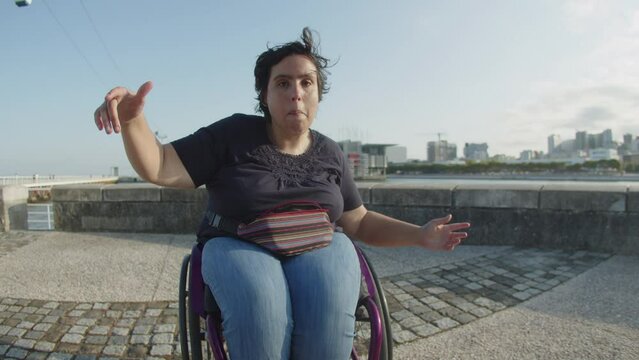 Portrait of young Woman with disability dancing using wheelchair outdoors. Smiling Caucasian woman walking at quay. Woman with disability concept