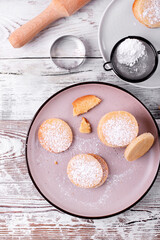 Fototapeta na wymiar Shortbread cookies of round shape covered with sugar powder on the plate. Top view