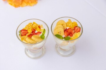 Top closeup of desserts in glass small bowls with fruits and yogurt on the white background