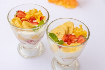 Top closeup of desserts in glass small bowls with fruits and yogurt on the white background