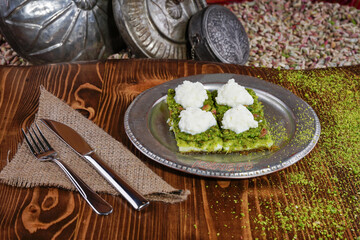 Kadayif with pistachio and cream in a plate on a wooden presentation board