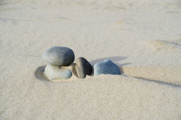 Stones are covered with quartz sand on beach during strong wind.