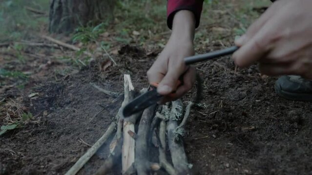 Closeup shot of a camper using flint and a knife to make fire in a forest