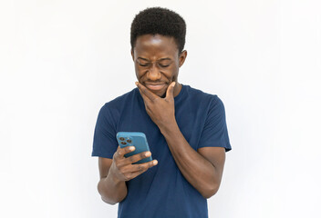 Doubtful man looking at phone. Young African American male model in blue T-shirt holding smartphone with doubt, getting suspicious message. Portrait, studio shot, technology, doubt concept