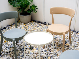 Empty white round shape side table near the empty green and yellow pastel colors chairs seats on...