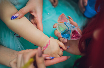 woman draws on a child's many hand. Close up.