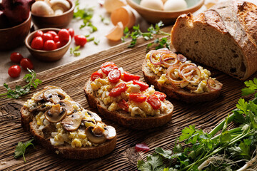 Sandwiches with scrambled eggs and vegetables on a wooden board