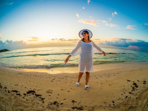 Woman walking on sunny, tropical beach at daybreak 