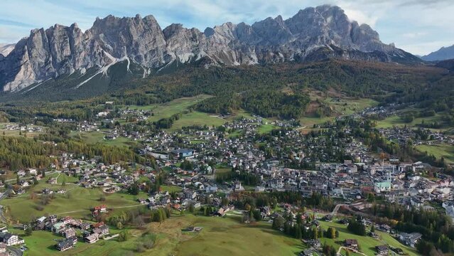 Alpine village under a mountain range in the center of a valley. Aerial video, Cortina d' Ampezzo, in the center of the Dolomites.