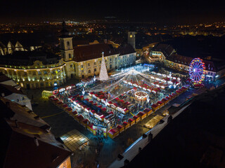 Landscape photography of Sibiu city center with the Christmas Fair, shot from a drone at sunset with the city lightning on. Birds eye view over cityscape of Sibiu, Romania.