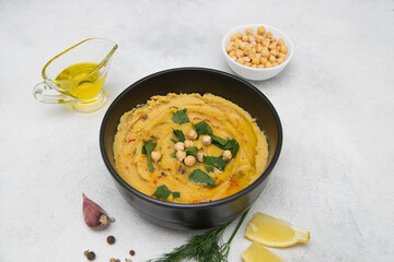 Hummus with spices, lemon, herbs, olive oil on a gray background.