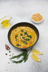Hummus with spices, lemon, herbs, olive oil on a gray background.