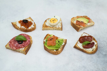 Variety of tapas sandwiches for aperetif on gray background. Top view.