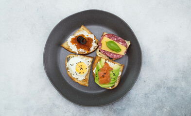 Variety of tapas sandwiches for aperetif on plate on gray background. Top view.