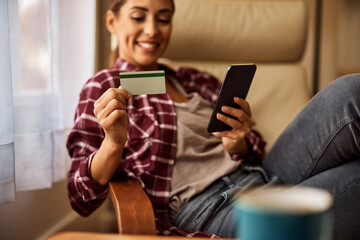 Close up of woman home shopping with credit card and cell phone at home.