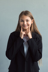 Fototapeta na wymiar Beautiful happy teen girl wearing black jacket and braces put fingers on her jowls and smiling