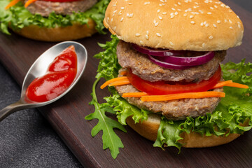 Beef burger with greens, chopped onions and carrots on board.