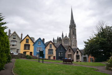 Fototapeta na wymiar Colorful row of houses with towering cathedral in background in the port town of Cobh, County Cork, Ireland