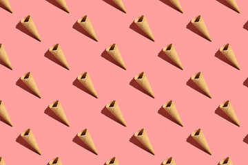 a hard light pattern of an empty waffle ice cream cone on bright colorful pink background, flat...