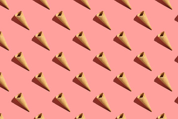 a hard light pattern of an empty waffle ice cream cone on bright colorful pink background, flat lay, top view